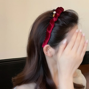 Serre-tête élégant en velours bordeaux avec perle et breloque dorée sur cheveux bouclés