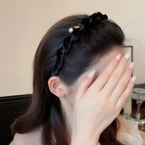 Serre-tête élégant en velours noir tressé avec perle et pendentif doré sur un mannequin