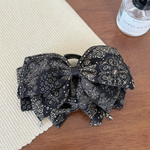 Close-up of retro paisley print bow hair claw clip with elegant crystal teardrop pendants