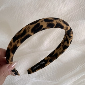 Pink leopard print fabric headband with a wide design and a handmade label on the inside