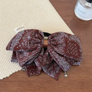 Detail of vintage paisley bow hair claw clip with dangling crystals on a woven mat