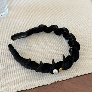 Détail du serre-tête tressé en velours noir avec perle, emblème doré et peigne intérieur