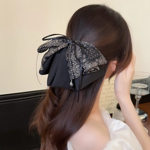 Detail view of double-layered black paisley bow hair clip with elegant crystal teardrop pendants