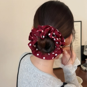 Elegant burgundy red polka dot scrunchie made of chiffon shown on a low hair bun