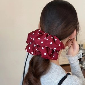 Elegant red polka dot silk scrunchie hair tie shown in a natural hairstyle setting