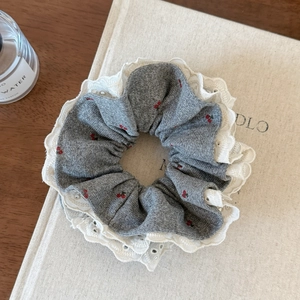 Detail of grey knitted hair scrunchie with red cherry embroidery and white lace trim