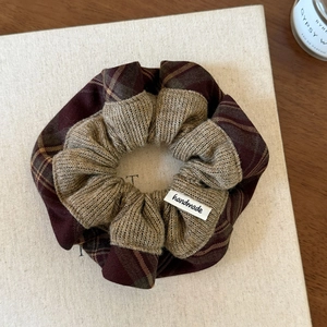 Detail of burgundy plaid and oat knit patchwork scrunchie with handmade fabric label