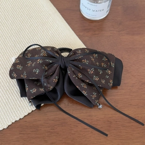 Close-up of vintage floral bow hair clip with black ribbons and crystal bead accents