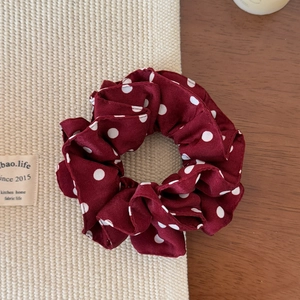 Detail of red polka dot scrunchie made of soft chiffon fabric on a textured background