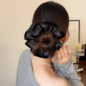 Gros plan d'un chouchou en satin noir plissé porté sur un chignon élégant