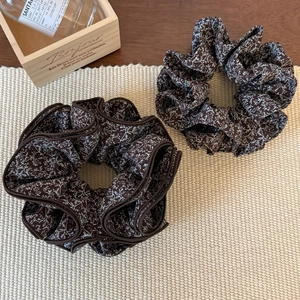 Close-up of two vintage floral scrunchies on a woven mat showing delicate petal patterns