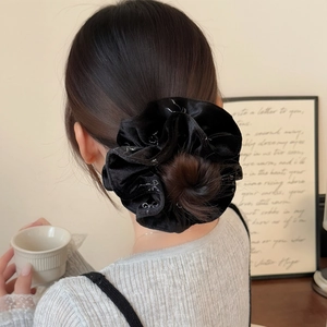 Elegant black velvet scrunchie with silver accents on a bun hairstyle for women