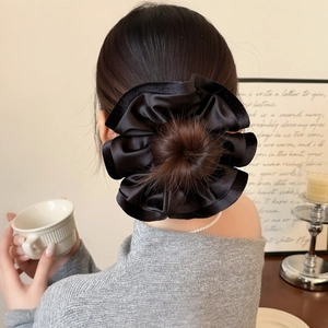 Gros plan d'un chouchou en satin noir à volants sur un chignon élégant et volumineux