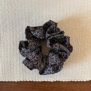 Detailed close-up of brown floral scrunchie on woven mat with vintage style aesthetic