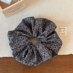 Detailed top view of a large floral scrunchie with white flower print on dark brown fabric