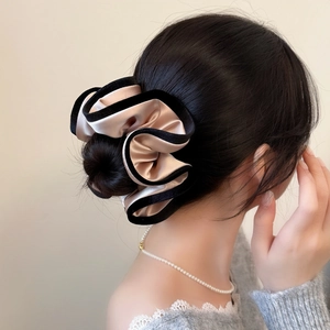 Détail d'un chouchou en satin doré champagne avec bordure noire sur un chignon