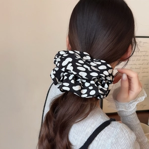 Chouchou large à pois noirs et blancs porté en queue de cheval pour un style chic