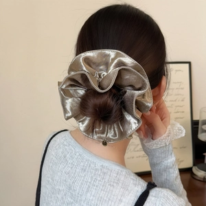 Gros plan d'un chouchou en satin doré champagne avec brillant métallique sur un chignon élégant
