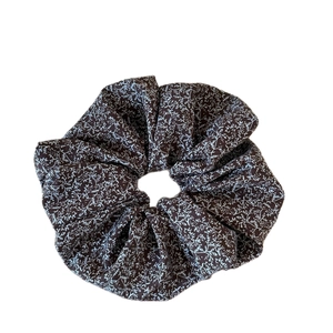 Vintage floral scrunchie with delicate white plant pattern on brown fabric texture