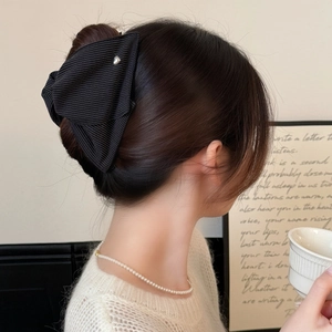 Dettaglio del fermaglio per capelli a righe nere con ciondolo a cuore su una donna