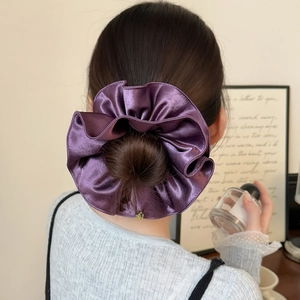 Vue détaillée du chouchou géant en satin violet brillant sur un chignon élégant