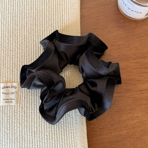Détail d'un chouchou noir en satin froissé avec bordure en velours sur une table