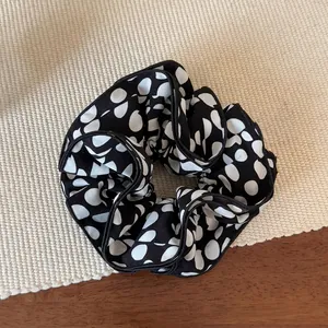 Gros plan du chouchou noir et blanc à pois sur un tapis de paille tressé