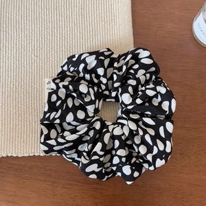 Gros plan du chouchou à pois noir et blanc avec texture satinée et étiquette de marque