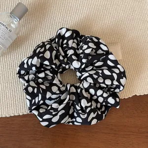 Détail d'un grand chouchou à pois noirs et blancs sur un tapis tressé minimaliste