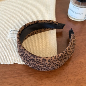 Detail of leopard print headband with soft suede texture on a warm wooden background