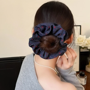 Detail of blue denim scrunchie with red polka dots worn in hair with elegant decor