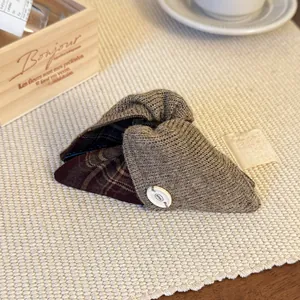Detail der gestrickten Haarklammer mit braunem Karostoff und BOTANI Gravur