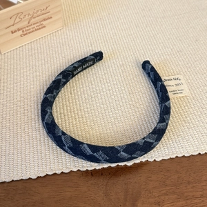 Detail of navy blue denim headband with geometric patterns and Hand Made woven label