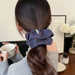 Navy blue denim scrunchie with red polka dots on a ponytail in cozy home setting