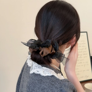 Detail of elegant brown satin hair scrunchie with black mesh bow on low ponytail