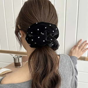 Detail showing high-quality black velvet scrunchie with white heart pattern and LOVE label