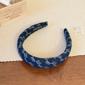Close-up of handmade navy blue denim headband with white diamond pattern and inner label
