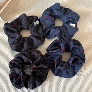 Set of 4 denim scrunchies with red polka dots and handmade label on a neutral background