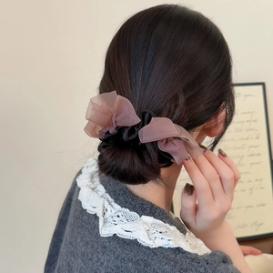 Detail of elegant pink organza double bow hair scrunchie on a classic black satin band