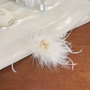 Vue détaillée d'une pince à cheveux en plumes blanches sur du tissu en soie