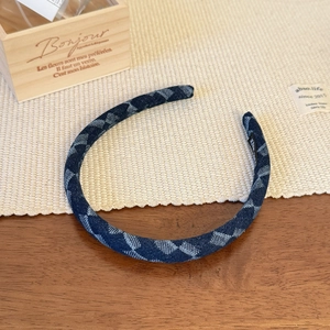 Detail of blue denim headband with white checkered pattern on a rustic wooden table