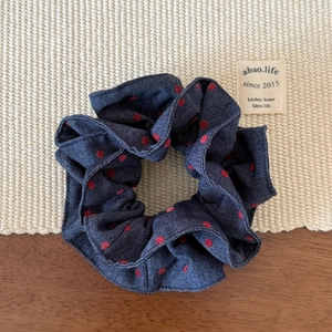 Detailed view of the dark blue denim scrunchie with classic red polka dot patterns
