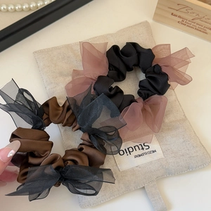 Detail of satin organza scrunchies set with bows on a rustic fabric background