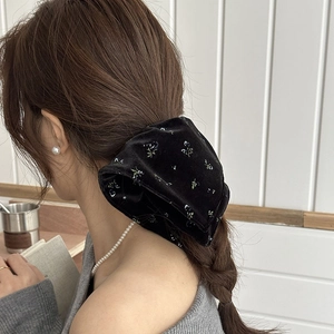 Detail of elegant black velvet hair scrunchie with blue floral pattern on model