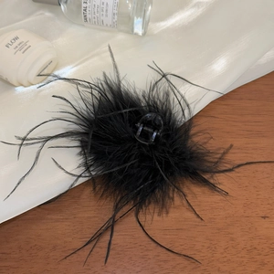 Détail d'une pince à cheveux en plumes noires sur tissu en soie et fond en bois chic