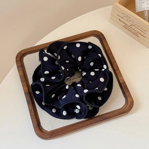 Close-up of double-layered polka dot scrunchie with ruffled edges on a wooden tray