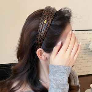 Leopard print headband with gold metal tag on model, wide retro style hair accessory