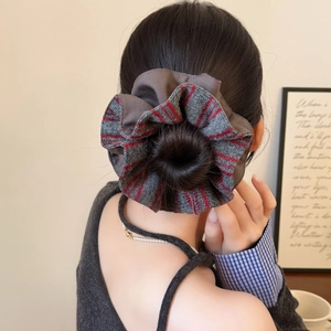 Striped knit scrunchie with grey and reddish-brown tones worn on a bun hairstyle