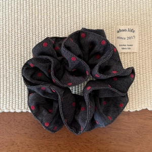 Macro shot of double-layered denim fabric scrunchie with red polka dots on beige mat