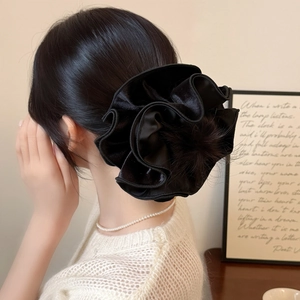 Close-up of a large black velvet scrunchie showing elegant pleated flower texture on hair
